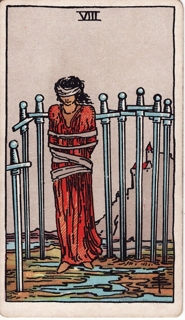 Tarotkortet Åtta i svärd – en bunden kvinna står omgiven av svärd – representerar begränsning, rädsla och mental fångenskap.