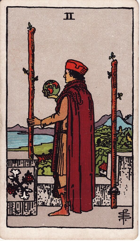 Tarotkortet Två i stavar – en man står med en jordglob och blickar ut över landskapet – representerar planering, framtidsvision och val.